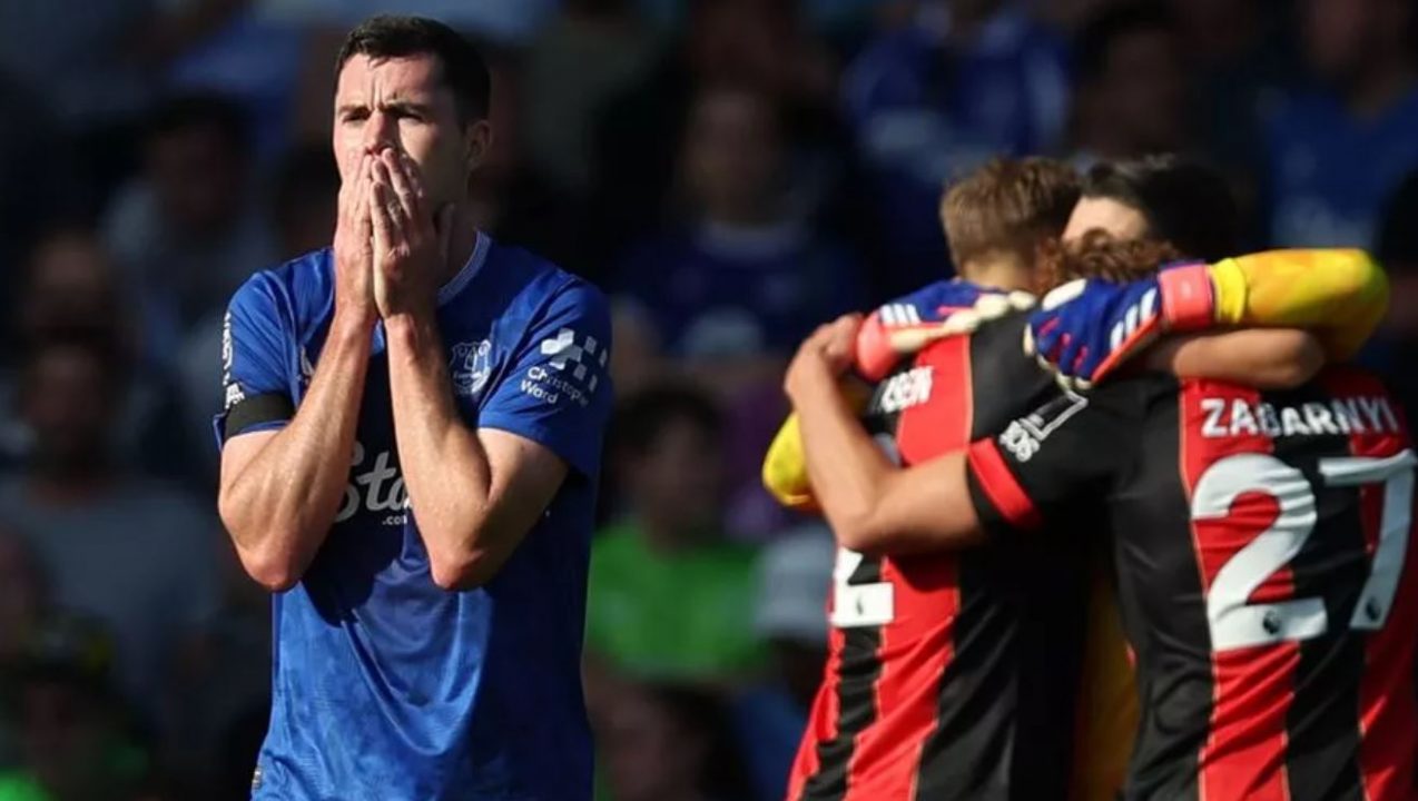 Everton 2-3 Bournemouth: Luis Sinisterra Cetak Gol Kemenangan di Menit ke-96, Cherries Balikkan Keadaan dan Tambah Penderitaan Toffees Awal musim yang suram bagi Everton berlanjut setelah Bournemouth bangkit dari ketertinggalan dua gol untuk meraih kemenangan luar biasa di Goodison Park. Tim asuhan Sean Dyche tampak melaju menuju kemenangan pertama mereka di Premier League musim ini setelah gol dari Michael Keane dan Dominic Calvert-Lewin. Namun, dalam waktu lima menit yang menegangkan, Cherries berhasil menyamakan kedudukan. Antoine Semenyo mencetak gol dengan penyelesaian tenang di tiang jauh untuk memperkecil ketertinggalan sebelum kapten tim tamu, Lewis Cook, menyundul bola melewati Jordan Pickford. Masih ada waktu bagi Luis Sinisterra untuk mencetak gol kemenangan yang sensasional, menambah penderitaan bagi Dyche dan para pemainnya saat rekor tanpa kemenangan mereka berlanjut.