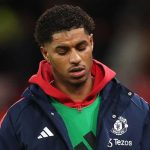 Marcus Rashford mengenakan jaket cadangan Manchester United