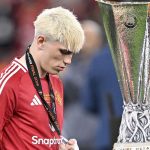 Alejandro Garnacho berjalan tertunduk melewati trofi Liga Europa