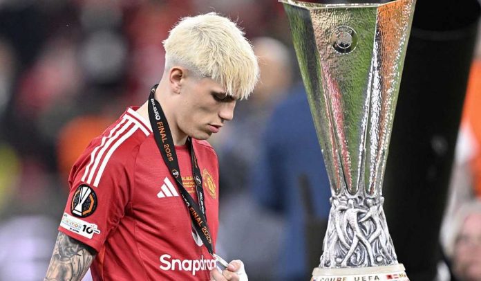 Alejandro Garnacho berjalan tertunduk melewati trofi Liga Europa