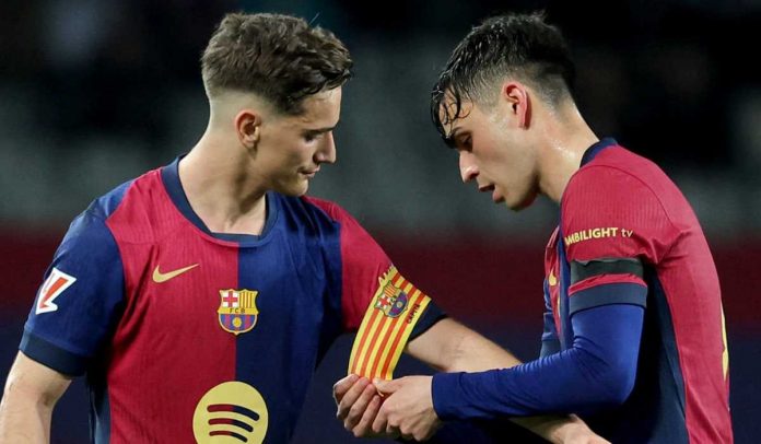 Pedri memakaikan ban kapten Barcelona ke lengan Gavi